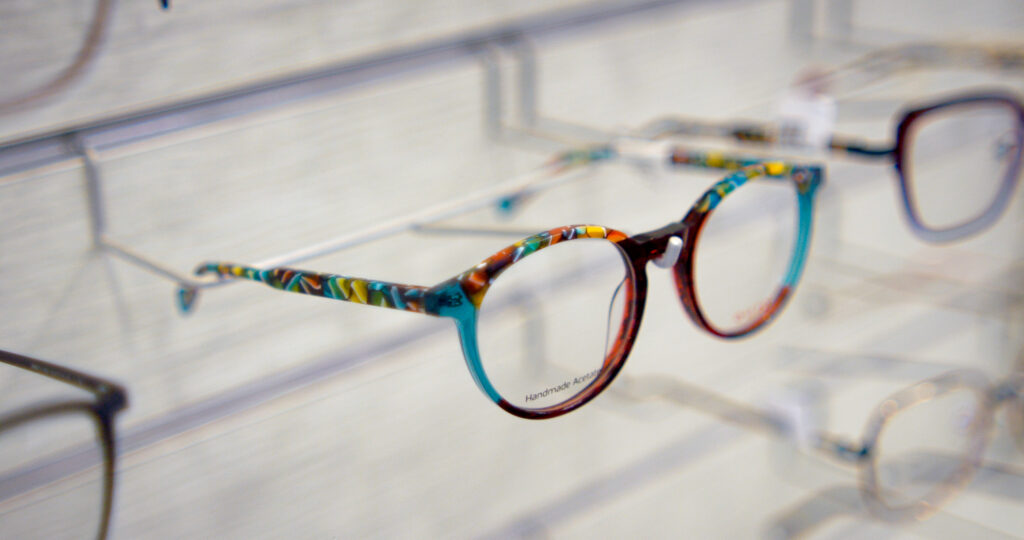 Close-up of colorful patterned eyeglasses on a display shelf in a bright store environment.